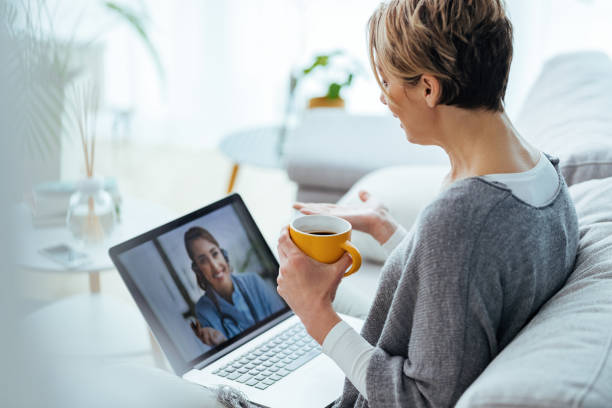 woman sitting on the sofa while making video call over laptop with her doctor. woman sitting on the sofa while making video call over laptop with her doctor.