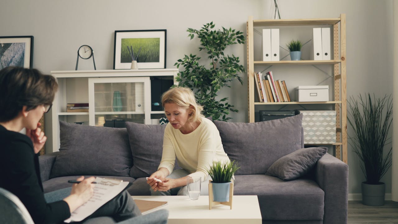Mastering the First Impression: Your intriguing post title goes here A woman consults with a therapist in a modern, cozy home setting, focusing on mental health.