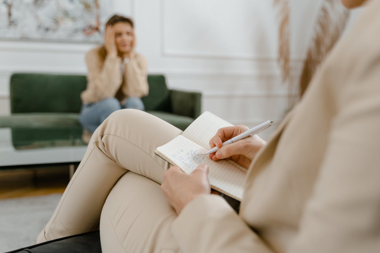services-img A therapist taking notes during a consultation with a patient, focusing on mental health.